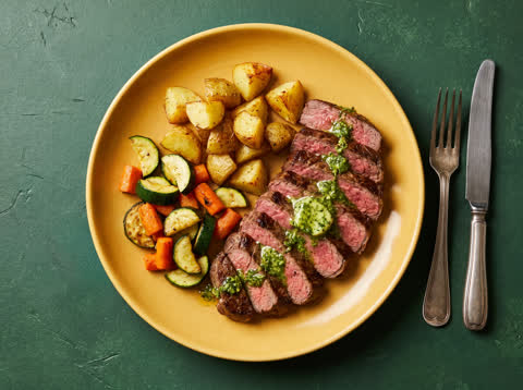 Rump steak with pesto butter, roast potatoes and veggies